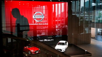 In this July 25, 2019, file photo, a man rides an escalator as Nissan vehicles are showcased in the Nissan Gallery in Yokohama, west of Tokyo. Nissan, reeling from a scandal over its former superstar executive Carlos Ghosn, sank into red ink in the latest quarter as its vehicle sales fell around the world, and the Japanese automaker slashed its profit forecast for the year.