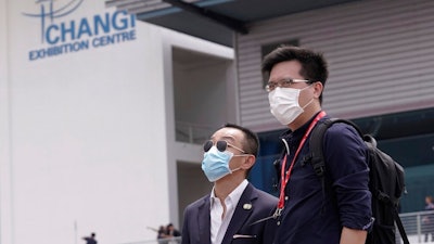 Visitors wear masks at the Singapore Airshow in Singapore Tuesday, Feb. 11, 2020. Singapore's air show began Tuesday with the usual ribbon cutting and displays of aerial prowess, but also with less typical warnings to industry and military figures attending to avoid handshakes and other close contact to avoid spreading a virus that has sickened tens of thousands of people.