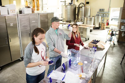 From left, Caitlin Bagenstose, Logan Snyder and his wife Carly Snyder bottle hand sanitizer made at the Eight Oaks Farm Distillery in New Tripoli, PA on Monday, March 16.