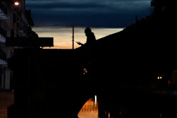 In this March 10, 2020 file photo, a woman wearing a face mask checks her phone as she walks at the Naviglio Grande canal in Milan, Italy.