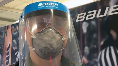 A Bauer Hockey employee models a medical face shield the hockey equipment manufacturer has begun creating to help those treating the coronavirus pandemic.
