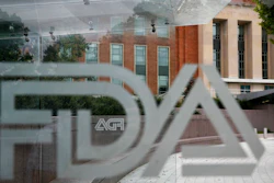 This Aug. 2, 2018, file photo shows the U.S. Food and Drug Administration building behind FDA logos at a bus stop on the agency's campus in Silver Spring, Md. Health officials reported the first U.S. drug shortage tied to the viral outbreak that is disrupting production in China, but they declined to identify the manufacturer or the product. The Food and Drug Administration said late Thursday, Feb. 27, 2020, that the drug's maker contacted health officials recently about the shortage, which it blamed on a manufacturing issue with the medicine's key ingredient.