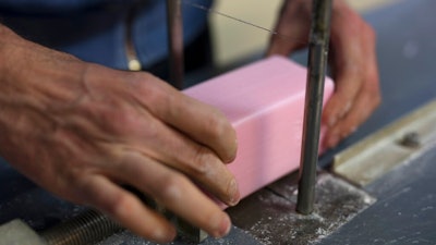 In this photo taken Monday March 16 2020, a factory worker cuts soap into bars at the Licorne soap factory in Marseille, southern France.