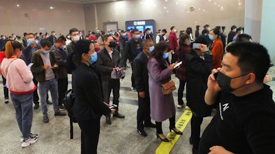 Travelers wearing masks line up to buy train tickets at a railway station in Yichang in central China's Hubei province Wednesday, March 25, 2020. Trains carrying factory employees back to work after two months in locked-down cities rolled out of Hubei province, the center of China's virus outbreak, as the government on Wednesday began lifting the last of the controls that confined tens of millions of people to their homes.