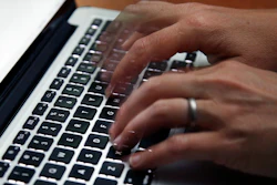 This June 19, 2017 file photo shows a person working on a laptop in North Andover, Mass. The U.S. internet won’t get overloaded by spikes in traffic from the millions of Americans now working from home to discourage the spread of the new coronavirus, experts say. But connections could stumble for many if too many family members try to videoconference at the same time.
