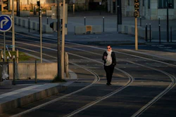 A woman walks on empty tram rails in Lyon, central France, Monday, March 23, 2020. French citizens are only allowed to leave their homes for necessary activities such as shopping for food, going to work or taking a quick walk due to the rapid spreading of the new coronavirus in the country. For most people, the new coronavirus causes only mild or moderate symptoms. For some it can cause more severe illness, especially in older adults and people with existing health problems.