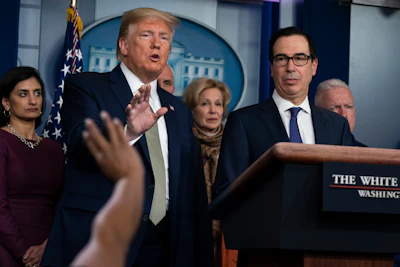 In this March 17, 2020 file photo Treasury Secretary Steven Mnuchin, right, listens as President Donald Trump speaks during a press briefing with the coronavirus task force, at the White House in Washington.