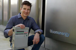 Joe Tavi, Bloom Energy senior director of manufacturing, holds a refurbished ventilator as he kneels beside fuel cells, Wednesday, April 1, 2020, in Sunnyvale, Calif.