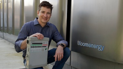 Joe Tavi, Bloom Energy senior director of manufacturing, holds a refurbished ventilator as he kneels beside fuel cells, Wednesday, April 1, 2020, in Sunnyvale, Calif.