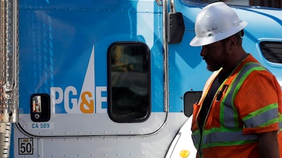In this Aug. 15, 2019, file photo, a Pacific Gas & Electric worker walks in front of a truck in San Francisco.