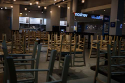 In this March 16, 2020 file photo, chairs hang stacked on empty tables at a closed restaurant in New York.