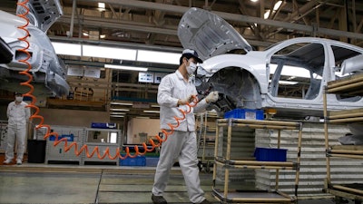 In this April 8, 2020, file photo, workers assemble cars at the Dongfeng Honda Automobile Co., Ltd factory in Wuhan in central China's Hubei province. China's auto sales sank 48.4% in March from a year ago as the economy reeled from the coronavirus, according to an industry group, adding to strains for the struggling industry in its biggest global market.