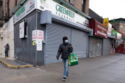 In this Friday, April 3, 2020, photo, a woman walks by local stores during the coronavirus pandemic in New York. Small business owners hoping for quick help from the government’s emergency $349 billion lending program were still waiting Tuesday, April 7, 2020, amid reports of computer problems at the Small Business Administration.