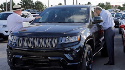 In this Thursday, Nov. 5, 2015, file photo, salesperson Andrew Montalvo, left, talks to a customer checking out the interior of a 2015 Grand Cherokee Limited in Doral, Fla. Fiat Chrysler is betting the SUV craze is here to stay and drivers around the world will want even more Jeeps. The company said Wednesday, Jan. 27, 2016, it predicts Jeep brand sales will nearly double to 2 million worldwide by 2018. (AP Photo/Alan Diaz, File)