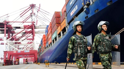 In this Sept. 8, 2016, file photo, paramilitary police patrol near a cargo ship at a port in Qingdao in eastern China's Shandong province. China imposed measures Tuesday, Feb. 13, 2018, against importers of a U.S. industrial chemical, requiring them to post deposits in preparation for possible anti-dumping duties amid rising trade tension with Washington.