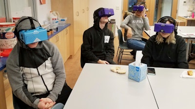 In this Feb. 7, 2018 photo, students at the Berkeley Carroll School in the Brooklyn borough of New York use virtual reality headsets in their classroom. Experts say the technology is still relatively rare in schools, but they expect that to change as costs come down and content improves. Seated at the table from left are Daniel Cornicello, 17, Charlie Hertz, 17, and Taylor Engler, 16. At the table in the back of the room is Angela Aguero, 17.