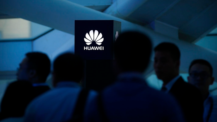 In this May 26, 2016, photo, attendees stand near a pillar with the Huawei logo during a launch event for the Huawei Matebook in Beijing. As trade disputes simmer, Chinese telecommunications giant Huawei, the No. 3 smartphone brand, is shifting its growth efforts toward Europe and Asia in the face of mounting obstacles in the U.S. market.