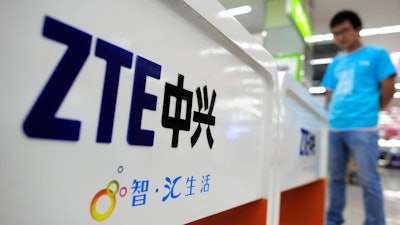In this Oct. 8, 2012, file photo, a salesperson stands at counters selling mobile phones produced by ZTE Corp. at an appliance store in Wuhan in central China's Hubei province. The tech company, ZTE, a Chinese tech giant brought to its knees and delayed shipments of imported U.S. cars, apples, lumber and other agricultural products are the early casualties as China and the U.S. exchange salvos in a trade dispute.