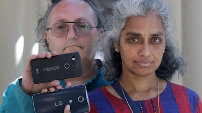 In this July 25, 2018 photo, Kalyanaraman Shankari, right, and her husband Thomas Raffill hold their phones while posing for photos in Mountain View, Calif.