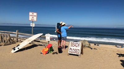 Two people look out at the shore after a reported shark attack at Newcomb Hollow Beach in Wellfleet, Mass, on Saturday, Sept. 15, 2018. A man boogie boarding off the Cape Cod beach was attacked by a shark on Saturday and died later at a hospital, becoming the state’s first shark attack fatality in more than 80 years.
