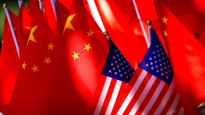 In this Sept. 16, 2018, photo, American flags are displayed together with Chinese flags on top of a trishaw in Beijing. A congressional advisory panel says the purchase of internet-linked devices manufactured in China leaves the United States vulnerable to security breaches that could put critical U.S. infrastructure at risk. The U.S.-China Economic and Security Review Commission issued the warning Wednesday in a report focused on the increasing use of the internet in household appliances.