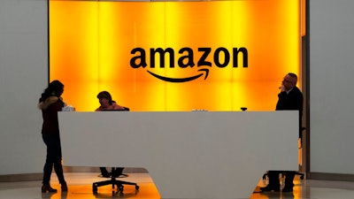 In this Feb. 14, 2019 file photo, people stand in the lobby for Amazon offices in New York. Amazon is providing a tool that will allow brands to remove listings from its site themselves that they consider to be for counterfeit goods. The online giant is also launching a product serialization service, which allows brands to put unique codes on their products during the manufacturing process. The codes are then scanned by Amazon to confirm authenticity once purchased.