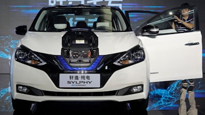 In this Aug. 27, 2018, file photo, a cameraman takes video of a Nissan Sylphy Zero Emission, the Nissan's first all-electric vehicle built in China, at the Nissan factory in Guangzhou, Guangdong province, China.