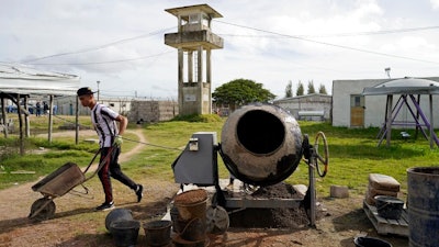 In this May 9, 2019 photo, an inmate works making concrete blocks, at a factory run by inmate Rolando Bustamante, at the Punta de Rieles prison in Montevideo, Uruguay. Bustamante's factory is one of dozens of inmate businesses in the prison, which has been transformed into an unusual experiment. Inmates form businesses, work for one another and offer products both to the world within the walls and to that without.