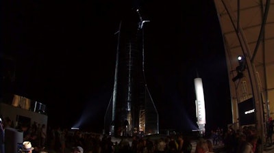 In this image made from video provided by SpaceX, Elon Musk, center, speaks of SpaceX's newly designed aircraft at its launch facility near Brownsville, Texas, Saturday, Sept. 28, 2019. Musk unveiled Saturday the SpaceX spacecraft designed to carry a crew and cargo to the moon, Mars or anywhere else in the solar system and land back on Earth perpendicularly.