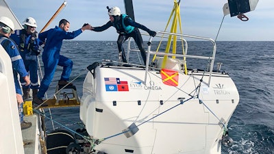 In this handout photo taken in Jan. 2020 and provided by Nekton, a diver helps a crew member onboard “Limiting Factor” submarine, part of sea trials of the Nekton Mission begins in mid-March.