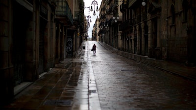 A man walks along an empty street in downtown Barcelona, Spain, Monday, April 20, 2020 as the lockdown to combat the spread of coronavirus continues.