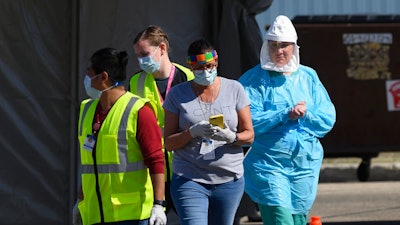 In this Saturday, April 18, 2020, photo, medical workers administer drive-up COVID-19 tests outside the Sanford Worthington Clinic in Worthington, Minn. The state has sent a team to ensure safe conditions in the southwestern Minnesota city, where multiple people have tested positive at a meatpacking plant.