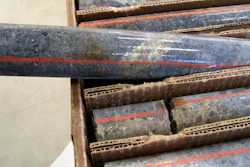 A core sample drilled from underground rock shows a band of shiny minerals.