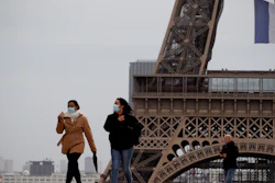 People walk near the Eiffel Tower, in Paris, Monday, May 11, 2020.