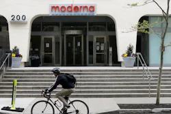 A bicyclist pedals past an entrance to a Moderna building, Cambridge, Mass., May 18, 2020.