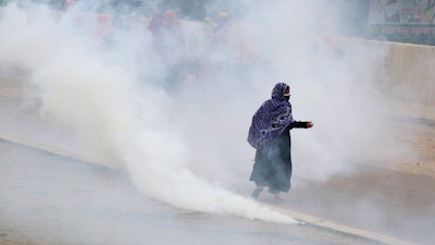 Bangladeshi garment workers run for cover after police fired tear gas to disperse them during a protest in Dhaka, Bangladesh, Wednesday, May 20, 2020.