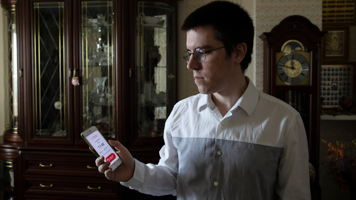 Vladimir Perevalov shows a Social Monitoring app installed on his phone in his apartment in Shcherbinka, outside Moscow, May 27, 2020.
