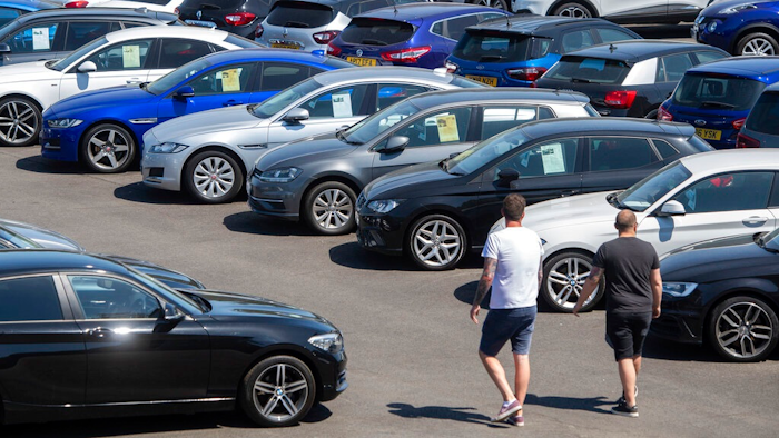 People view cars on the forecourt of a car sales outlet, in Norfolk, England, open for the first time since the lockdown, as part of a wider easing of restrictions in England, Monday June 1, 2020. The British government has lifted some lockdown restrictions to restart social life and activate the economy while still endeavouring to limit the spread of the highly contagious COVID-19 coronavirus.