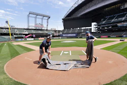 Grounds crew workers Jacob Weiderstrom, left, and Marcus Gignac pull a tarp off home plate at T-Mobile Park, Seattle, May 11, 2020.