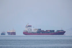 A cargo ship approaches the port of Piraeus as other ships are anchored.