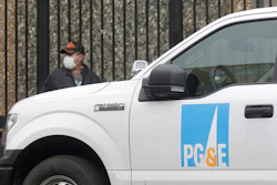A man wearing a mask walks behind a Pacific Gas and Electric truck in San Francisco.