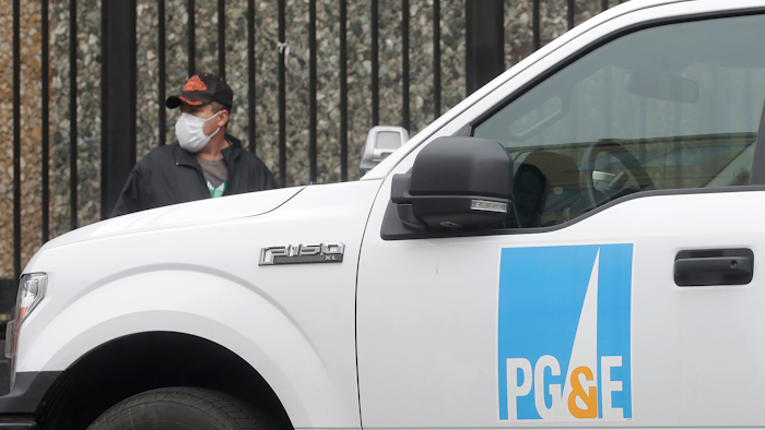 A man wearing a mask walks behind a Pacific Gas and Electric truck in San Francisco.