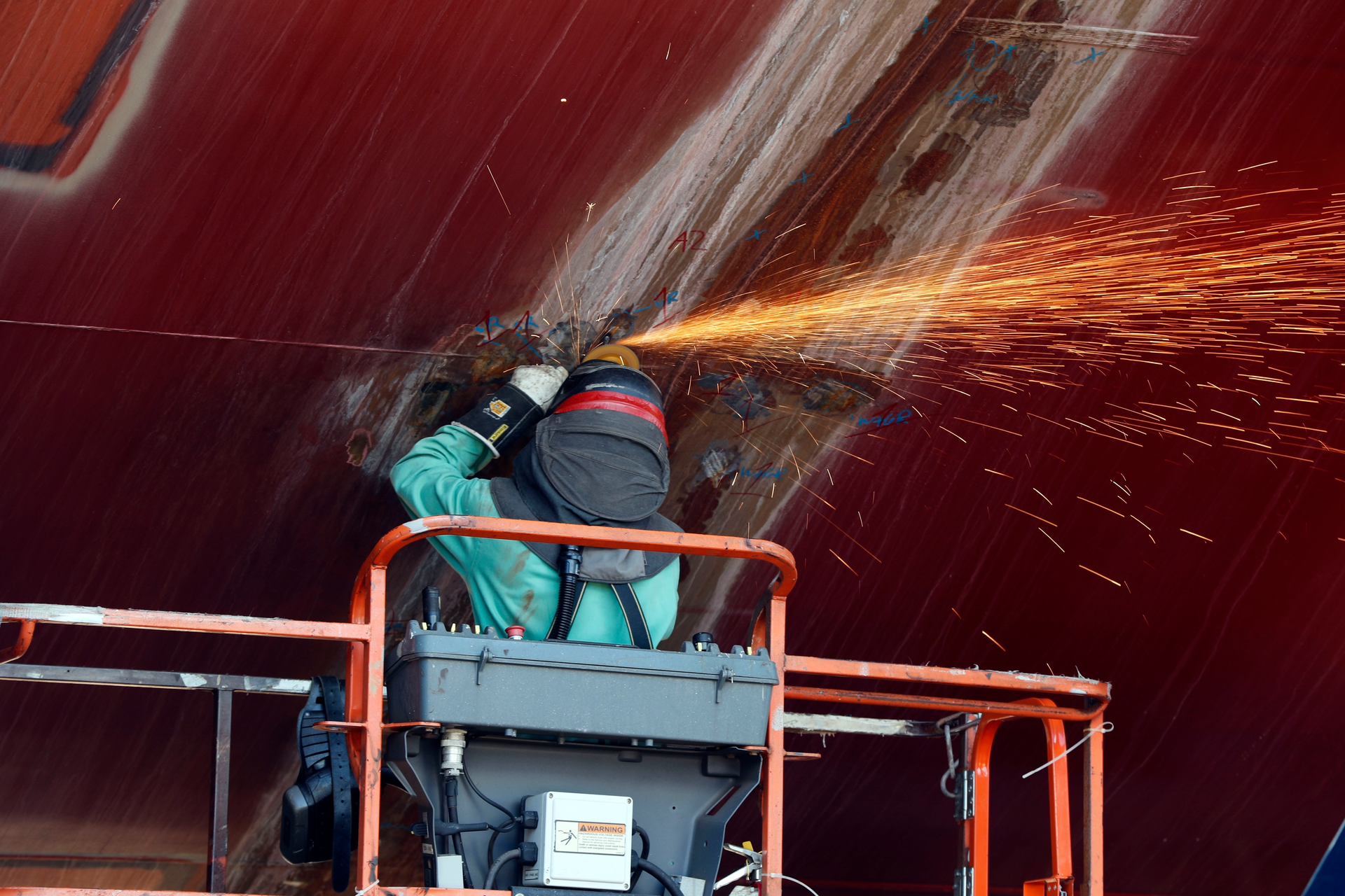 A welder works on the hull of a Zumwalt-class destroyer.