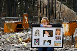 In this Feb. 7, 2019, file photo, Christina Taft, the daughter of Camp Fire victim Victoria Taft, displays a collage of photos of her mother, at the burned out ruins of the Paradise, Calif., home where she died in 2018. Pacific Gas & Electric officials are to be expected to appear in court Tuesday, June 16, 2020, to plead guilty for the deadly wildfire that nearly wiped out the Northern California town of Paradise in 2018.