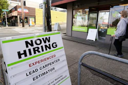 In this photo taken Thursday, June 4, 2020, a pedestrian wearing a mask walks past reader board advertising a job opening for a remodeling company, in Seattle. The U.S. unemployment rate fell to 13.3% in May, and 2.5 million jobs were added — a surprisingly positive reading in the midst of a recession that has paralyzed the economy and depressed the job market in the wake of the viral pandemic.