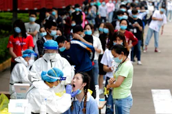 In this May 15, 2020 file photo, people line up for medical workers to take swabs for the coronavirus test at a large factory in Wuhan in central China's Hubei province. The Chinese city of Wuhan has tested nearly 10-million people for the new coronavirus in an unprecedented 19-day campaign to check an entire city.