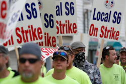 Striking shipbuilders picket outside an entrance to Bath Iron Works.
