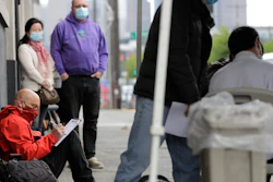 Glen Buhlmann, lower left, fills out a job application during a walk- and drive-up job fair in Seattle, May 16, 2020.
