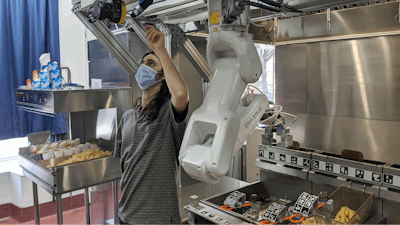 A technician makes an adjustment to a robot at Miso Robotics' White Castle test kitchen.