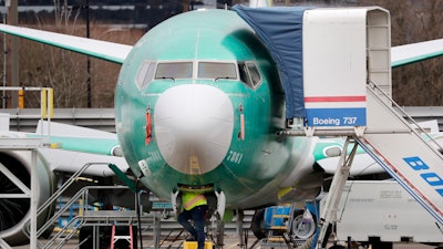 A worker looks up underneath a Boeing 737 Max jet in Renton, Wash., Dec. 16, 2019.